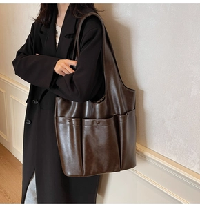 Close-up of a large vintage brown PU leather tote bag with multi-pocket details on a model