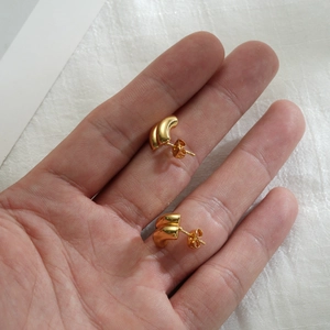 Minimalist 18k gold C-shaped hoop earrings held in hand to show compact size