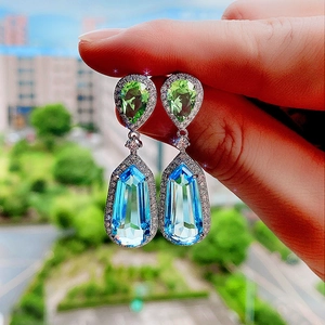 Detail of silver drop earrings with aquamarine zircon and pear-cut green gems