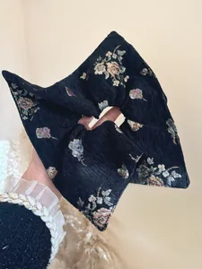 Close-up of a hand holding a vintage jacquard floral scrunchie in black textured fabric
