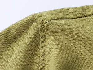 Close-up of olive green linen shirt shoulder seam showing high-quality stitching detail