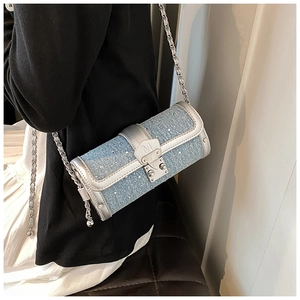 Detailed close-up of a blue denim cylinder bag with silver chain and rhinestones