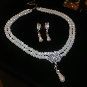 Close-up of double-layered pearl necklace and floral earrings set with diamond accents