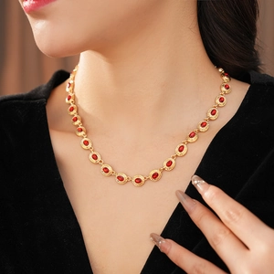 Gros plan d'un collier vintage doré avec pierres rouges ovales porté par un mannequin