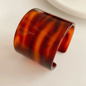 Macro shot of the wide open tortoise shell acetate bangle with translucent amber texture