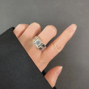 Men's silver ring with square-cut clear zircon stone shown on hand against grey background