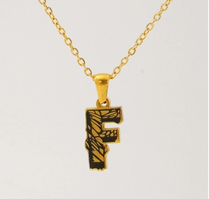 Close-up of gold-plated letter F pendant with black textured inlay on a fine chain