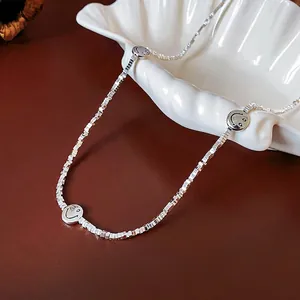Elegant silver-toned square-link chain necklace featuring three smiley face pendants on a shell
