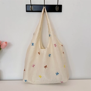Detail of embroidered colorful bow patterns on a beige tote bag with a minimalist design