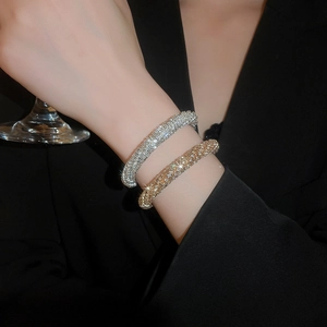 Elegant gold and silver pavé diamond bracelets worn by a woman holding a wine glass