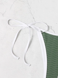 Macro shot of dark green bikini fabric with wave texture and white ties for beachwear