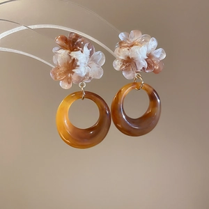 Detailed macro view of retro amber resin flower earrings with golden ring pendant