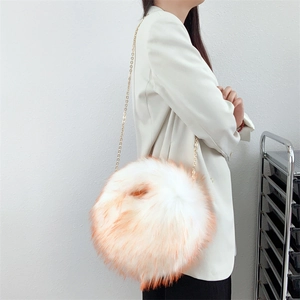 Close-up of white plush ball bag with orange-tipped faux fur and gold chain strap