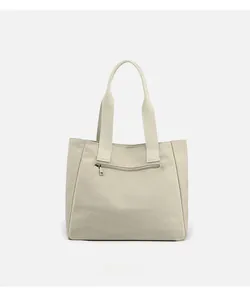 Detail of canvas shoulder bag back featuring a horizontal zipper pocket and reinforced handles