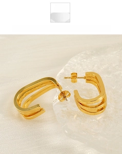 Detail of layered gold U-shape earrings featuring a polished triple-stack design and secure backing