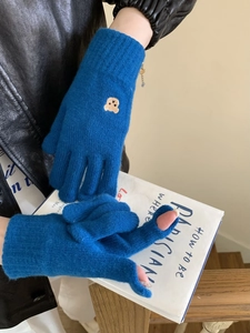 Detail of blue knitted gloves with bear embroidery and functional touch screen fingertips