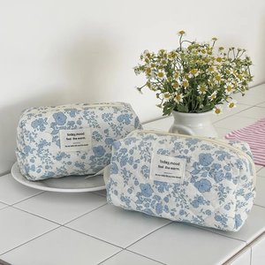 Close-up of blue floral quilted cotton makeup bags with zip closure and fabric label