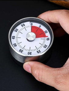 Macro view of stainless steel mechanical kitchen timer with 60-minute dial and red indicator