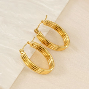 Detailed close-up of triple-layered golden oval hoop earrings with polished metal texture