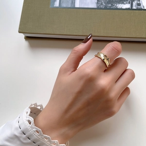 Irregular textured gold S925 silver ring with two dark gemstones worn on hand