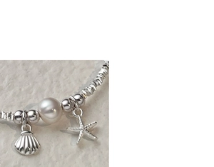 Macro shot of silver beaded bracelet with starfish, seashell charms and white pearl detail
