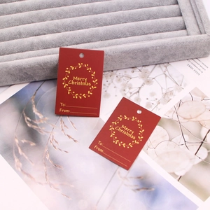 Detail of red Christmas gift tag with gold foil stamp Merry Christmas on velvet tray