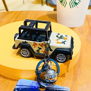 Detail of creative camouflage jeep keychain with silver bell and black carabiner hook