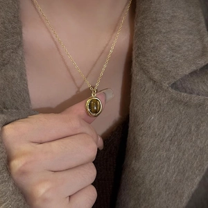Close-up of a vintage oval tiger eye pendant on a gold chain with autumn styling