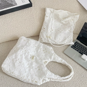 Detailed macro view of white floral lace fabric and delicate embroidery on tote bags