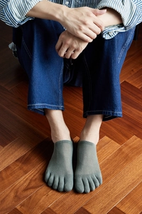 Close-up of men's grey five-toe socks with breathable mesh texture on wood floor