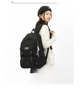 Detail of black nylon backpack with multi-pocket design and cartoon character pendant