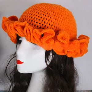 Detail of orange handmade crochet knit hat with ruffled brim on model head