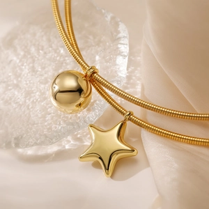 Double-layer stainless steel star necklace with gold finish on elegant beige fabric