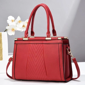 Détail du sac à main rouge en cuir grainé avec coutures en V et boucles dorées