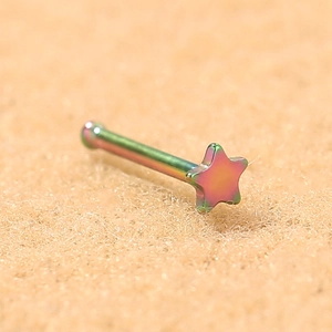 Close-up of a rainbow iridescent stainless steel star shaped nose stud on beige fabric