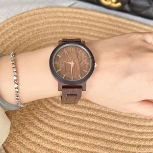 Women's dark brown wood grain watch with large dial and gold hands worn on wrist