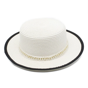 Detail of white boater straw hat featuring black piping and elegant pearl beaded band