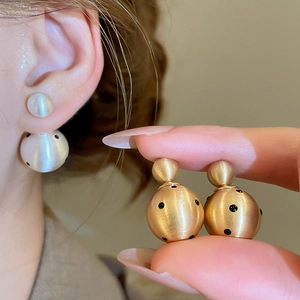 Detail of 18k gold plated double ball earrings with black polka dots and pearls