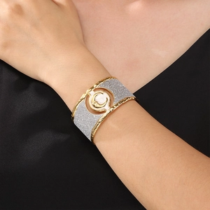 Macro detail of gold and silver tone cuff bracelet with frosted moon and star motifs