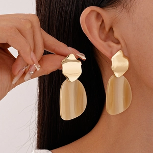 Boucles d'oreilles pendantes en résine avec accents dorés portées par un mannequin
