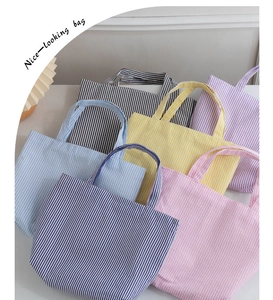 Detail view of various colorful striped canvas tote bags in a multi-color stacked display