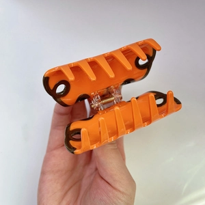 Detail of orange leopard print hair claw clip showing the resin texture and spring