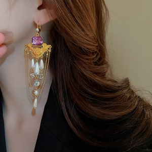 Gros plan sur des boucles d'oreilles baroques avec pierres violettes et perles blanches