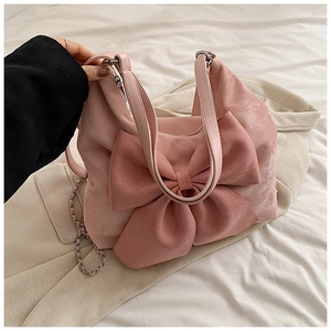 Detailed view of pink bow shoulder bag on beige blazer with mixed chain strap detail