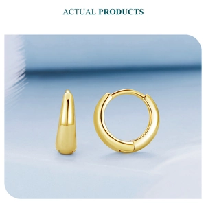 Detail of polished gold round hoop earrings with secure clasp on a soft feather background