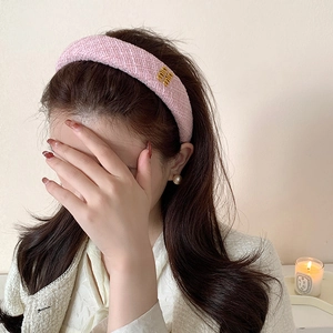 Cerchietto in tweed rosa con logo dorato su elegante foto lifestyle per modella