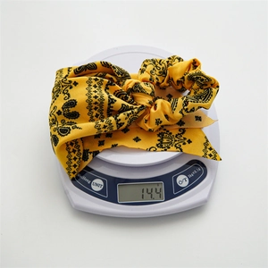 Detail showing paisley silk hair scrunchie on electronic scale weighing 14.4g
