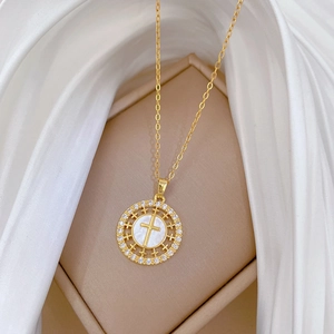 Macro shot of gold cross necklace with crystal pavé and white pearl inlay on silk