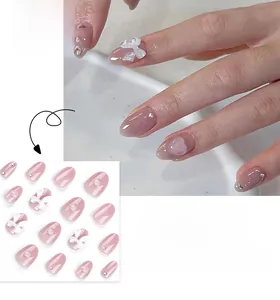 Faux ongles courts ronds rose poudré avec nœuds blancs 3D et détails en strass