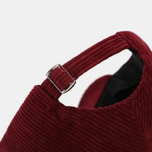 Detail of adjustable metal buckle and corduroy strap on the dark red baseball cap